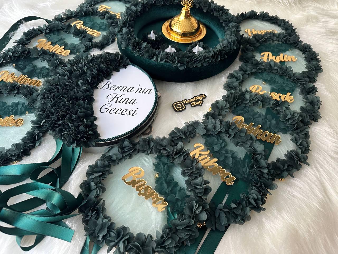 There are green bridesmaid tambourines and a bride tambourine with text. frame made by laser cut flowers and some satin tails. green henna basket