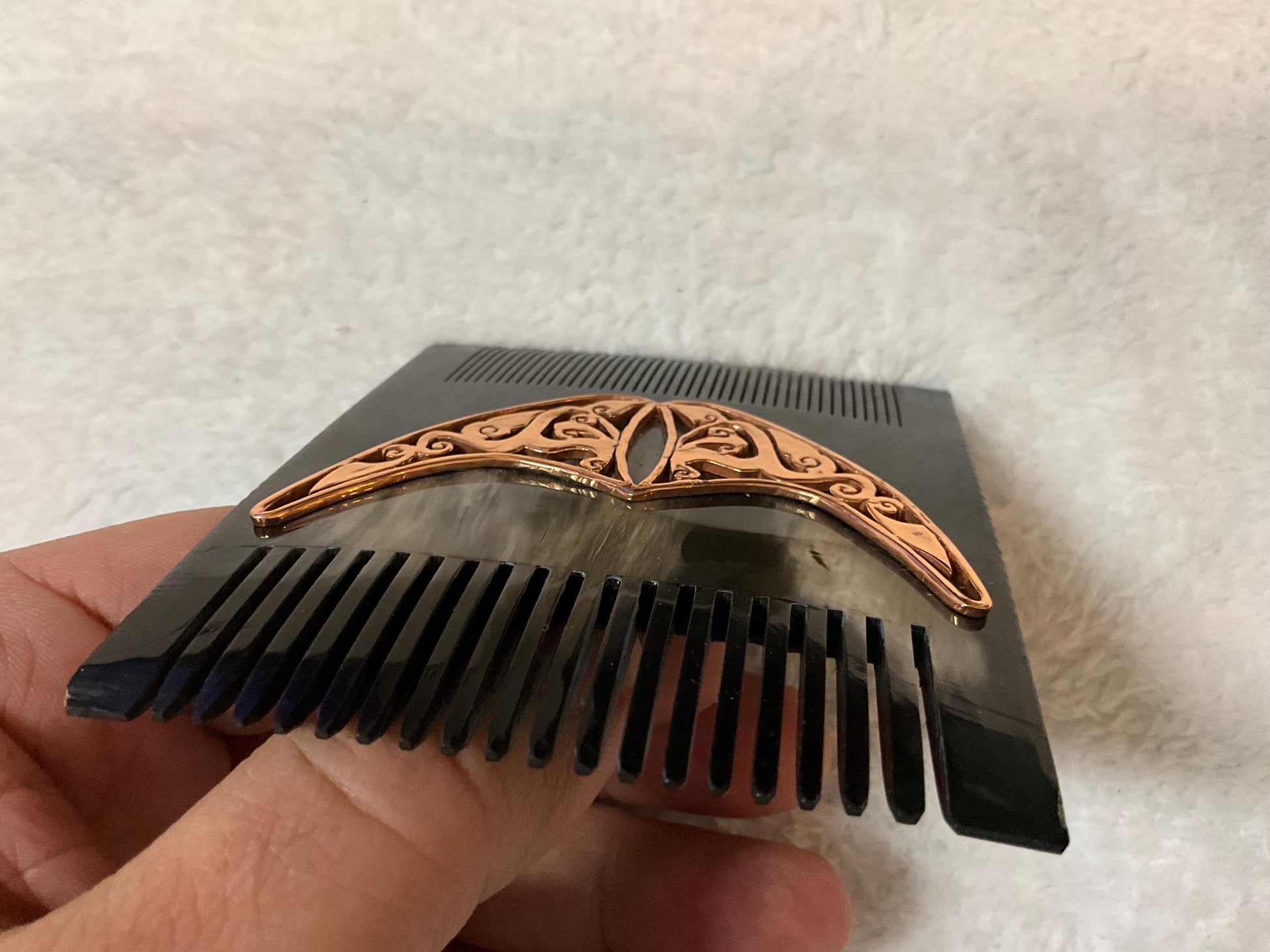 Natural black comb from upper side. It is over white carpet and it is seem as same size as a man.