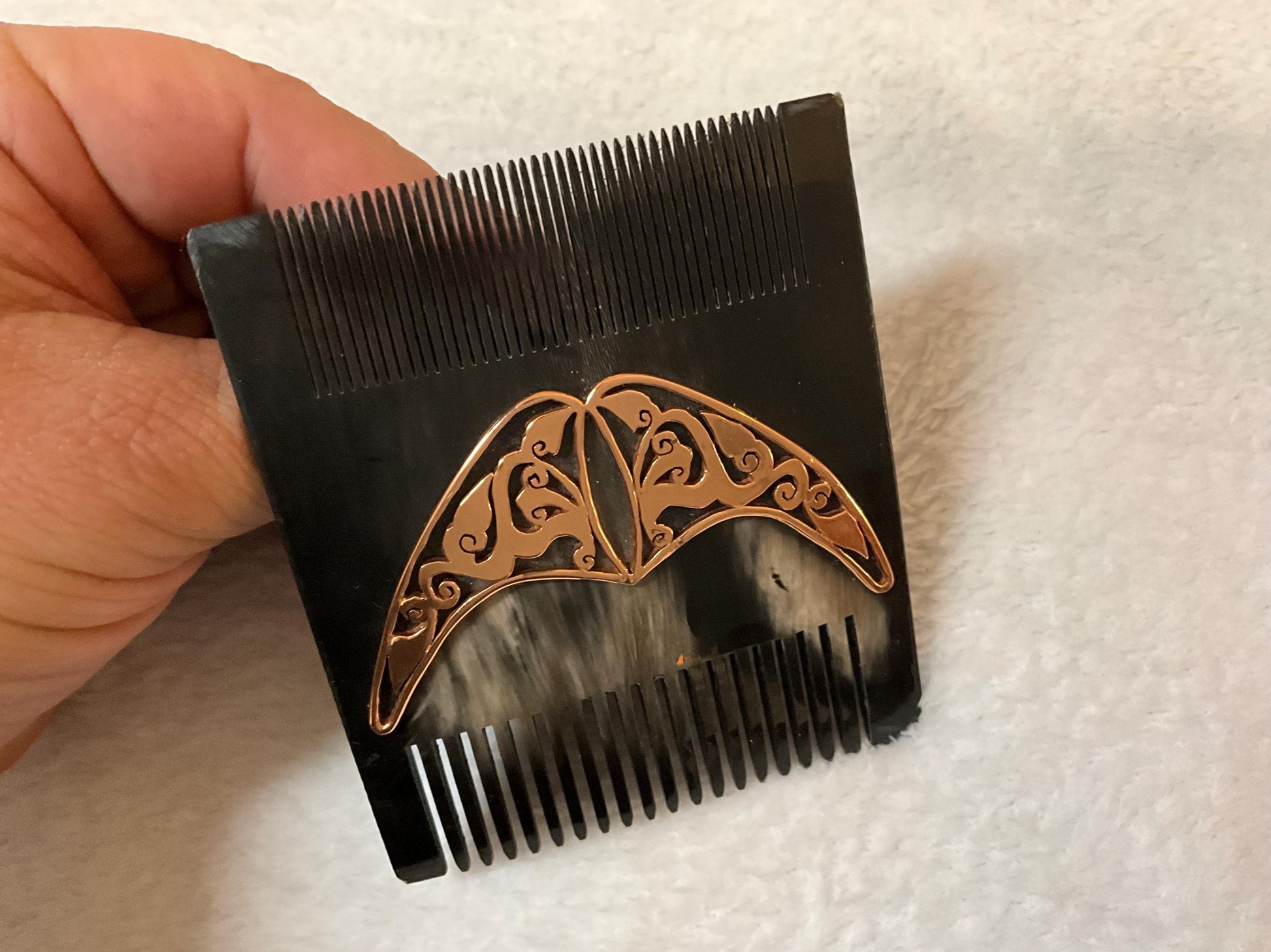 Natural black comb from front side. It is over white carpet and it is seem as same size as a man