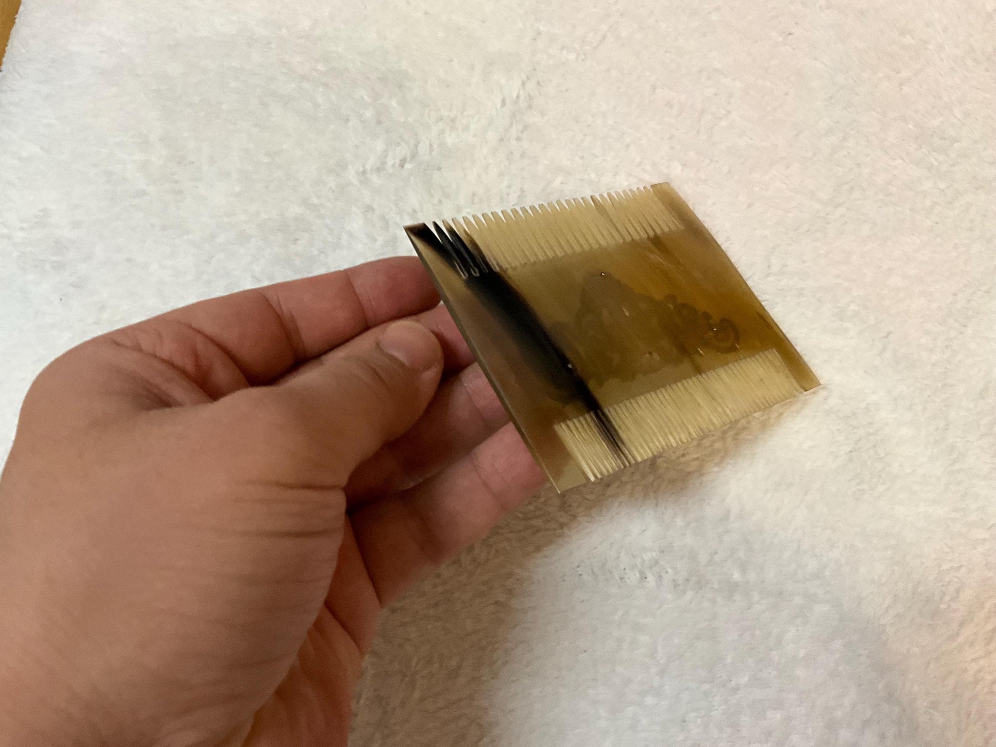 Natural light brown comb from back side. It is over white carpet and it is seem as same size as a man hand