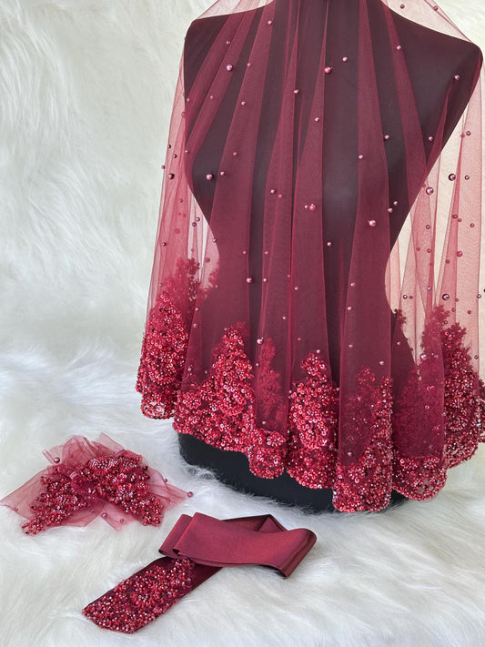 A burgundy bridal veil with pearl embellishments and a matching burgundy satin sash