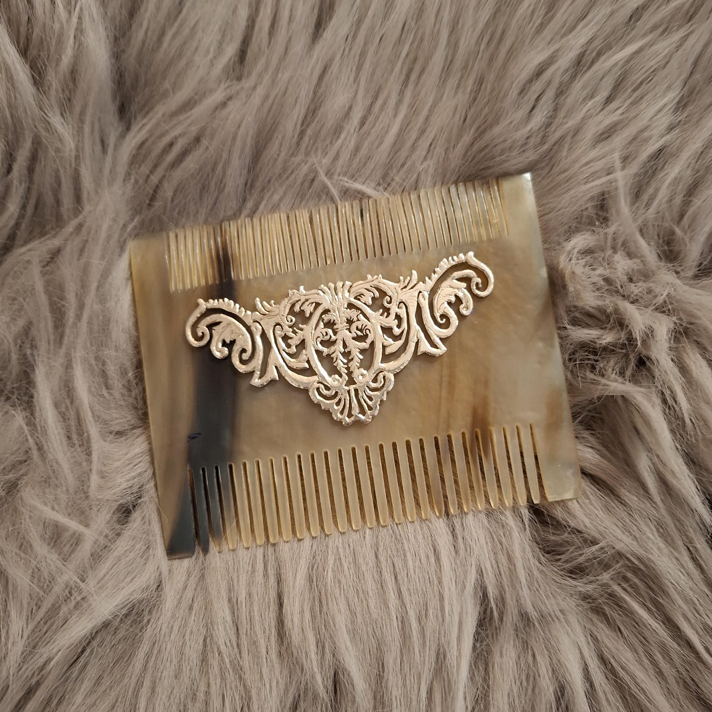 natural light brown horn comb is over beige fur. It is seen from front side