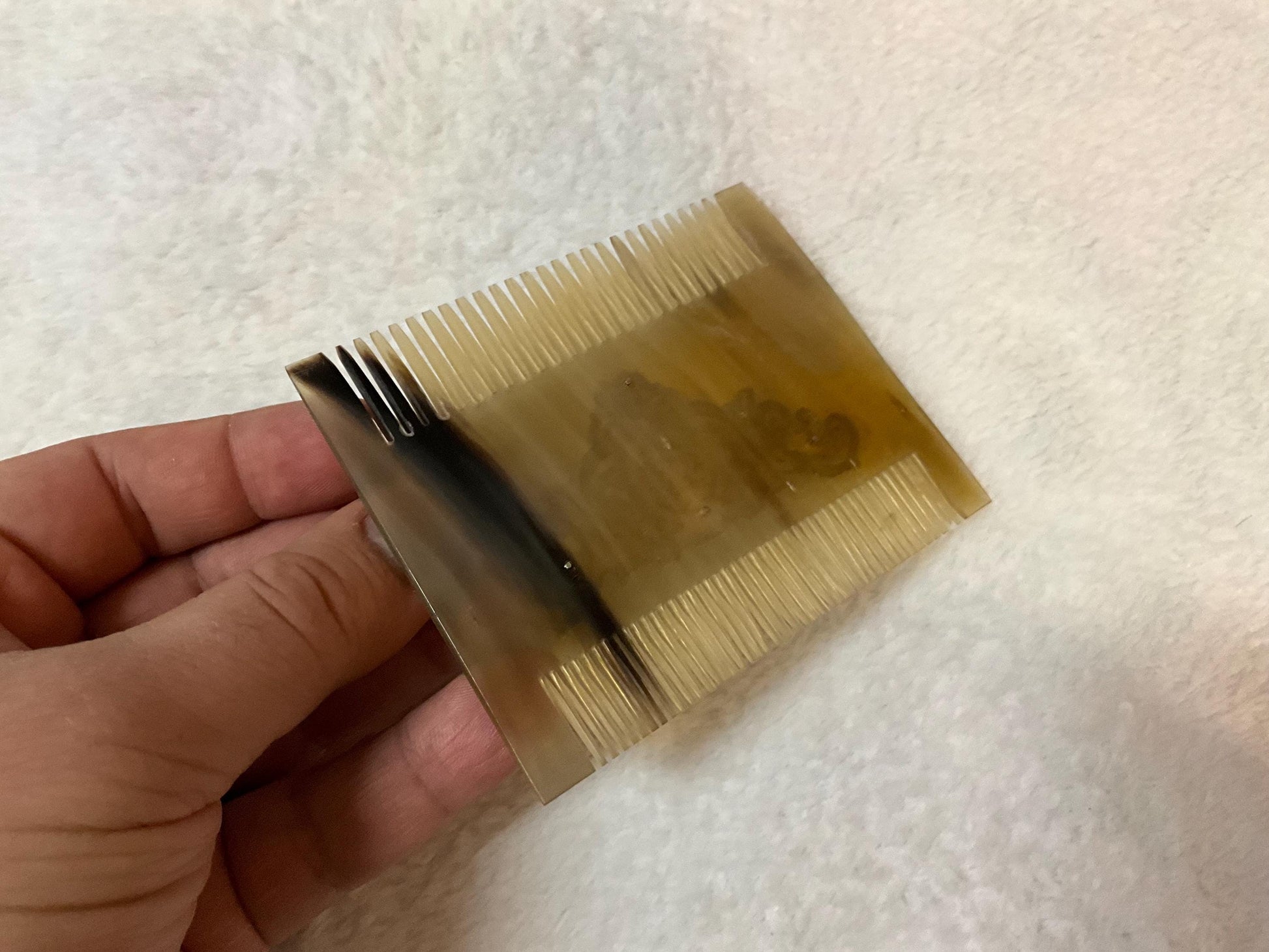 Natural light brown comb from back side. It is over white carpet and it is seem as same size as a men hand