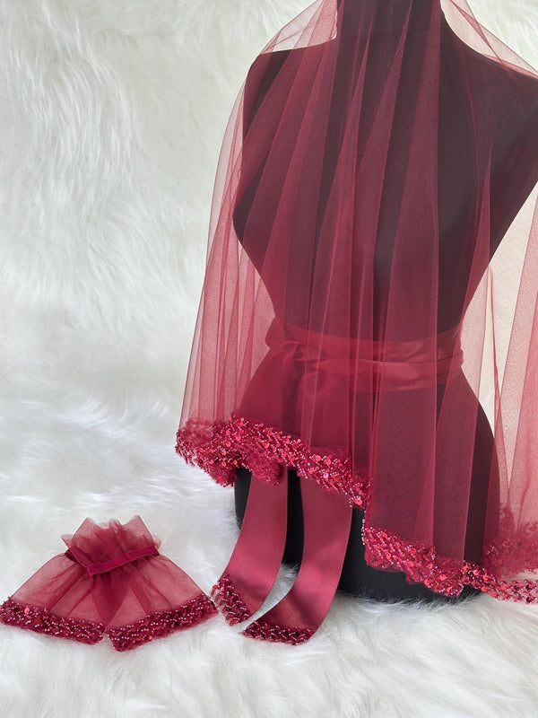 A burgundy bridal veil with a beaded trim and matching wrist cuffs. The veil is made of soft tulle and has a satin ribbon tie.