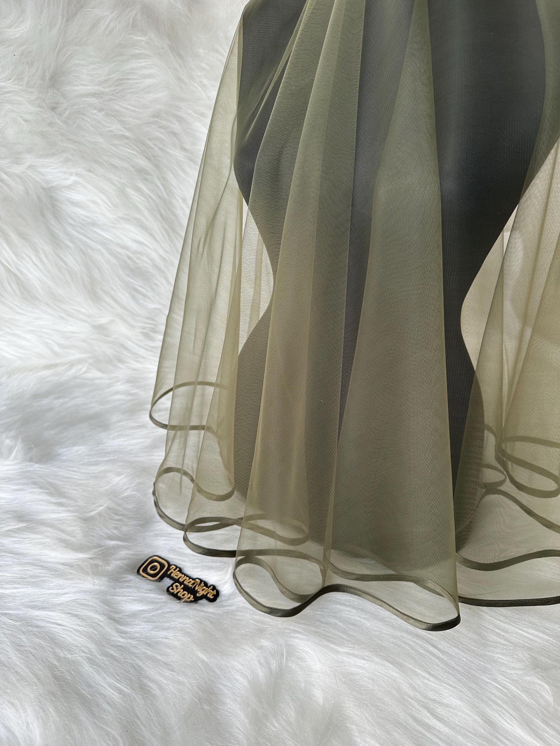 A sheer green veil with a scalloped edge and a satin trim. The veil is displayed on a mannequin against a white background