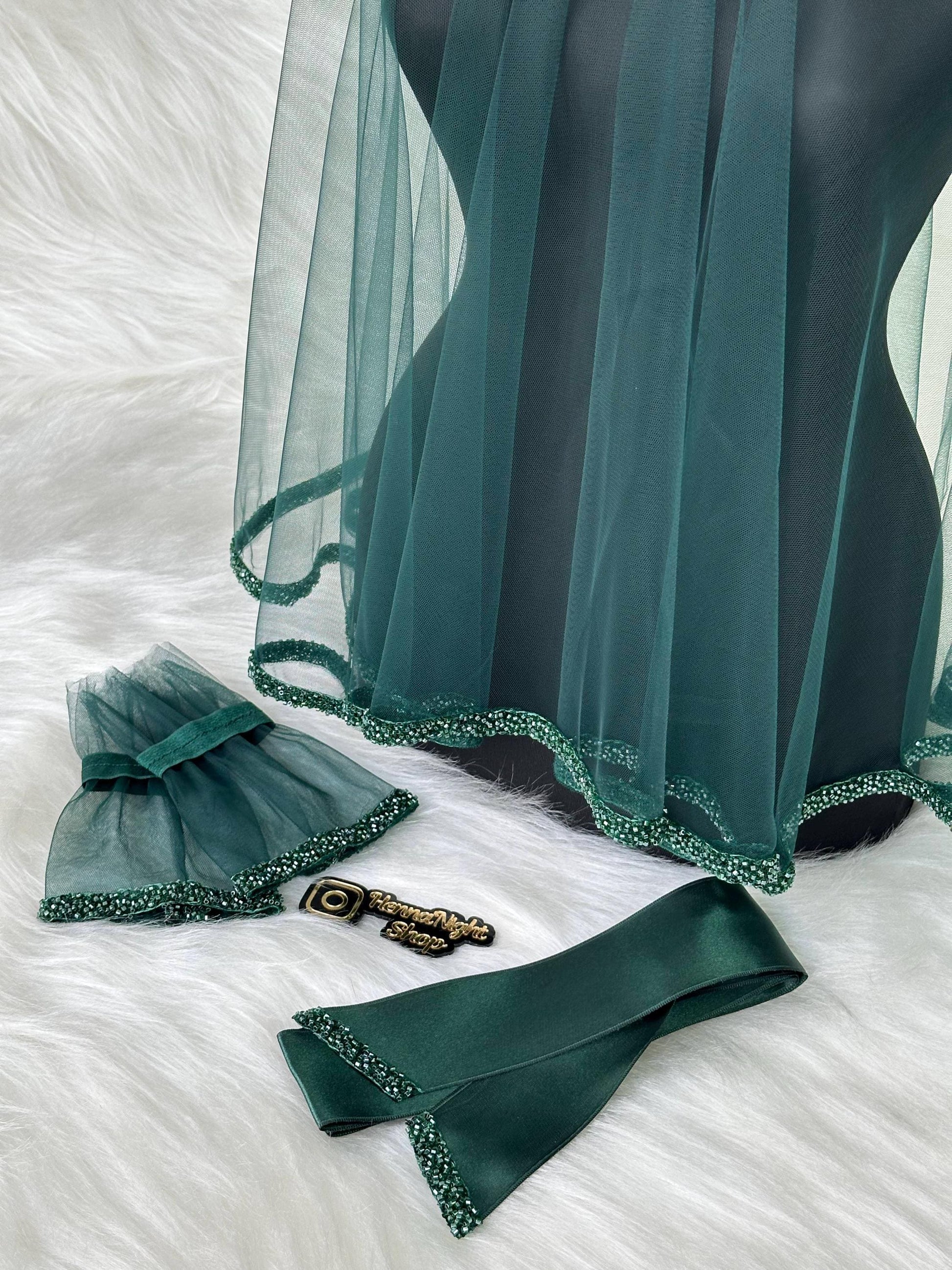 A dark green tulle veil with a beaded trim. The veil is displayed on a mannequin. There is a matching dark green satin sash with beaded trim and a pair of dark green beaded earrings. The earrings have a small gold charm with the text 'Handmade Magic Shop'.