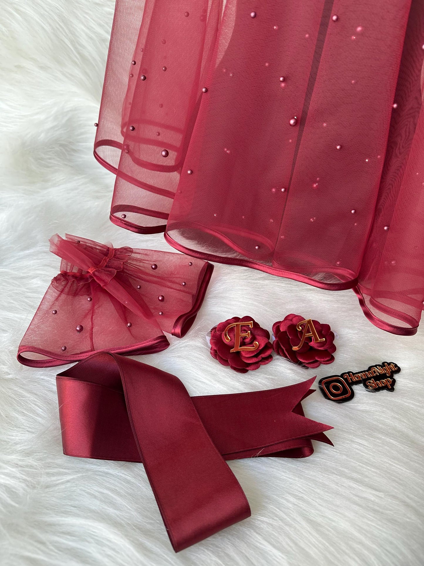 henna Burgundy tulle fabric with pearl embellishments, a burgundy satin ribbon, two burgundy fabric flowers with gold letters E and A, and a burgundy and gold Instagram logo with the text 'HannaNight Shop'.