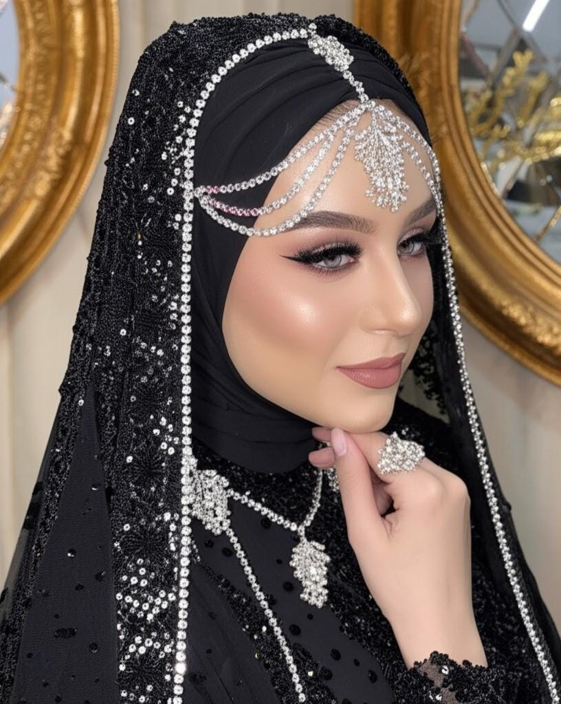 A gold necklace and earrings set with clear and silver-colored rhinestones. The necklace has a layered design with a large pendant in the center. The earrings are long and dangle. The set is displayed on a black mannequin. The text 'HennaNight Shop' is visible in the top center of the image.